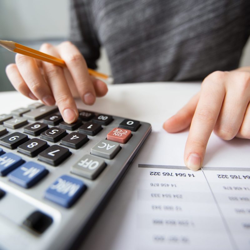 Closeup of accountant counting on calculator and working with table